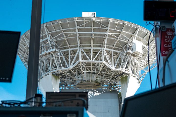 White radar dish with metal supports, viewed through window