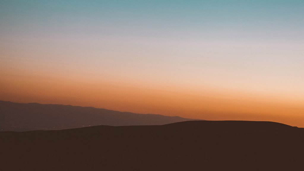 Rolling hills in front of a deep orange sunset
