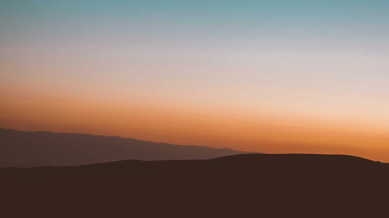 Rolling hills in front of a deep orange sunset