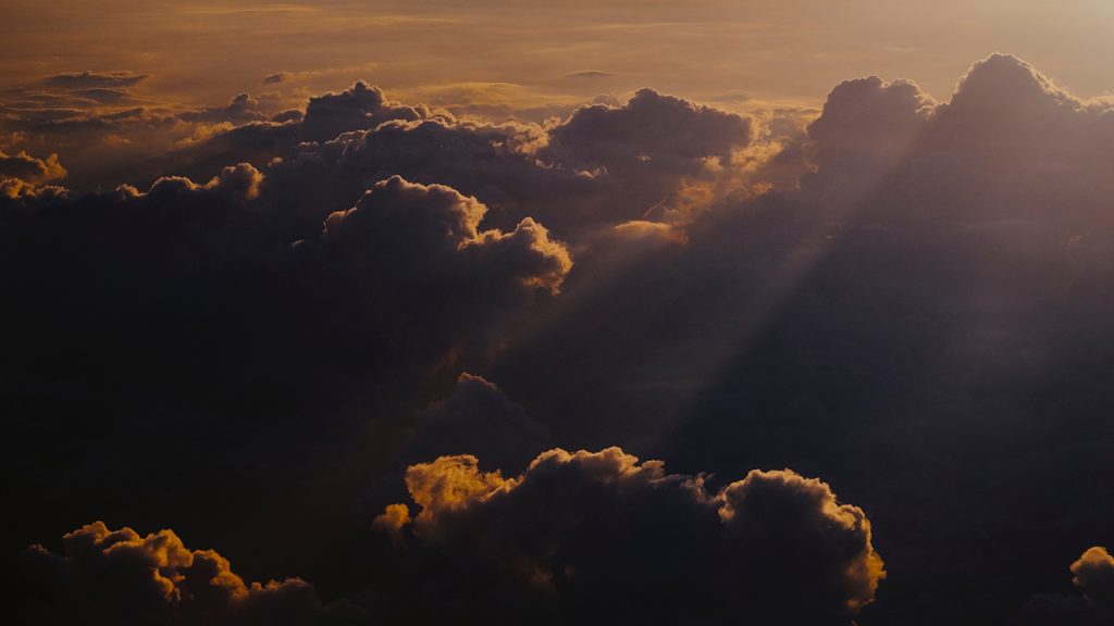 Golden sun shines through dark, fluffy clouds