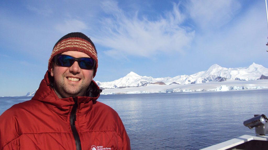 Person wearing red coat sits onboard a small boat in Antarctica