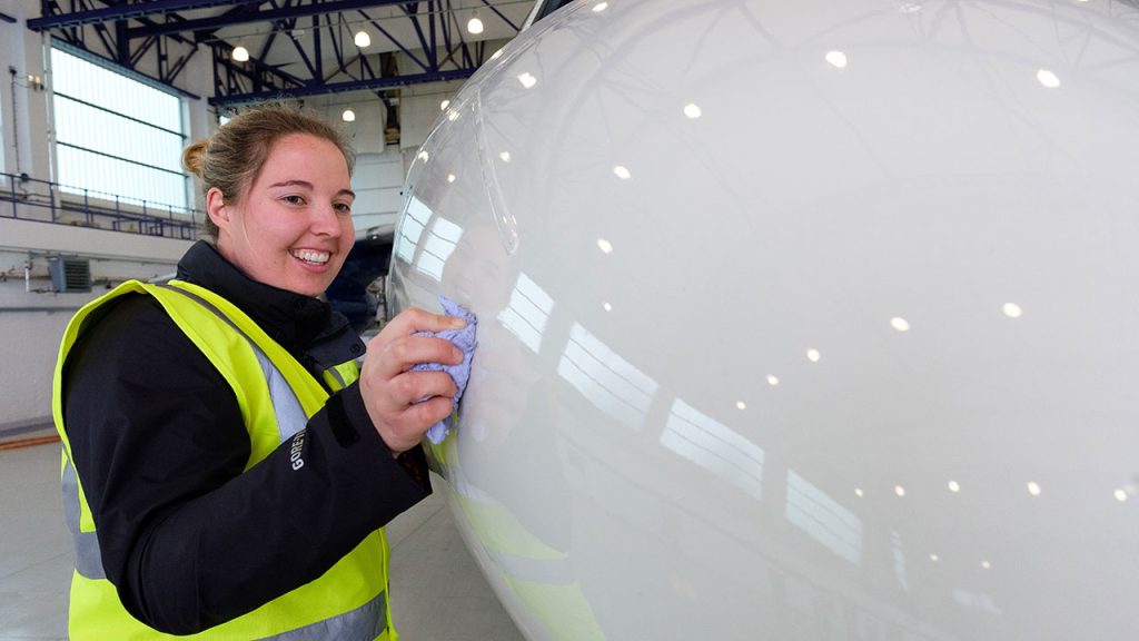 Person in high-visibility clothing stands touching research aircraft nose