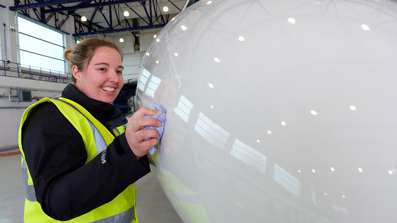 Person in high-visibility clothing stands touching research aircraft nose