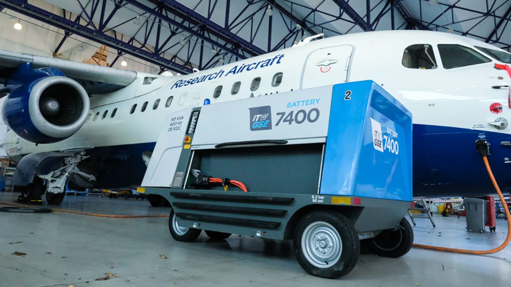 An electric ground power unit plugged in next to a white and blue aircraft