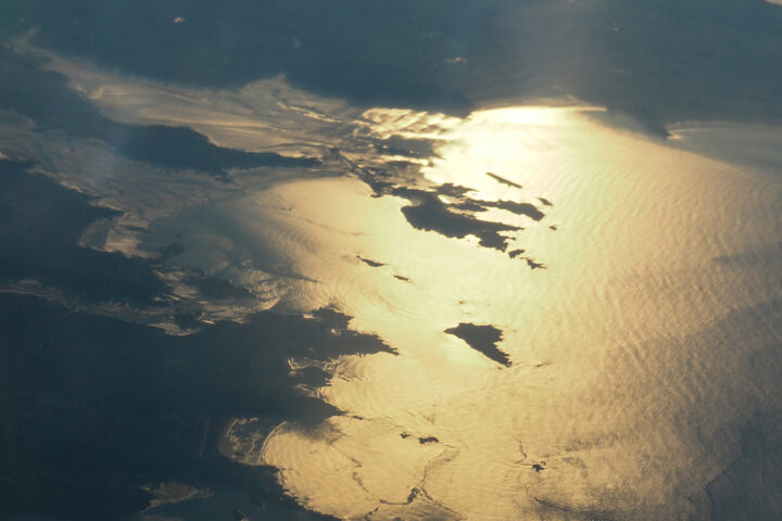 Golden sunlight reflecting on dark blue and grey ocean