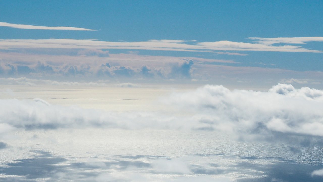 A bright blue sky with white clouds above a sparkling ocean