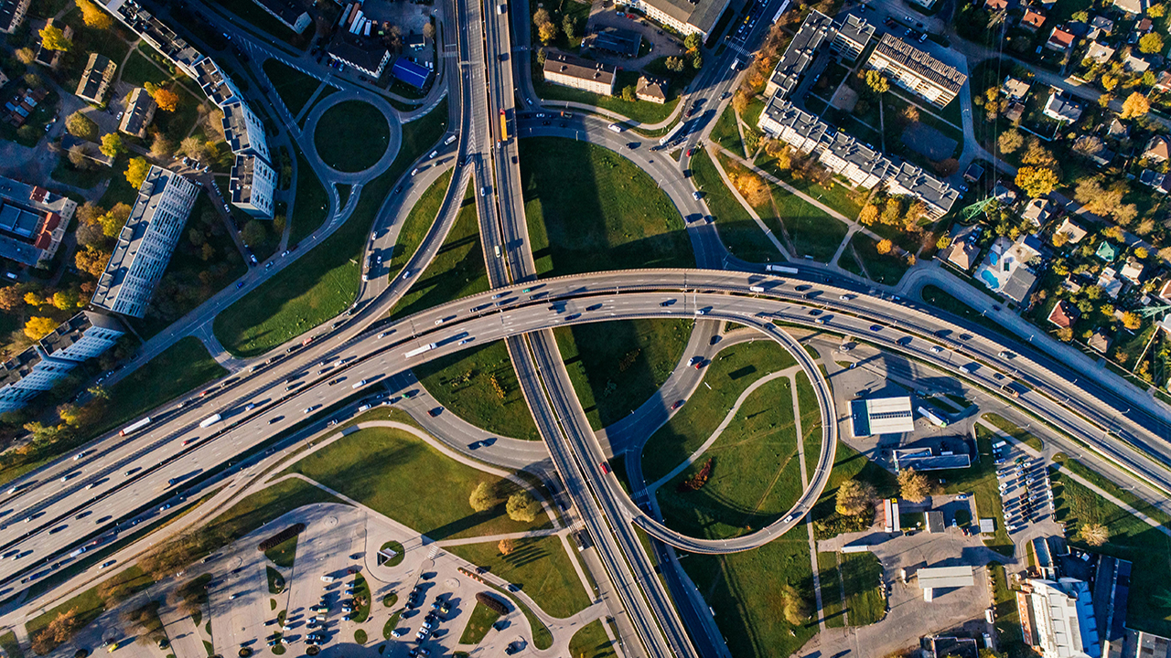 Aerial view of busy roads in an urban area, with some green space.