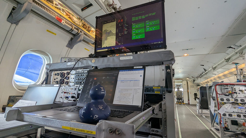 Plastic duck sits in front of a laptop showing data readings, on board an aircraft